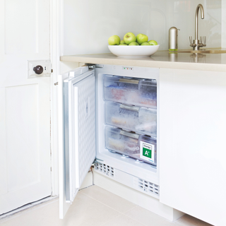 All white kitchen, fitted handleless units, limestone stone floor tiles, integrated freezer