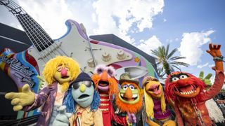 The Muppets Electric Mayhem standing in front of the Rock ' N' Roller Coaster guitar outside the ride at Walt Disney World