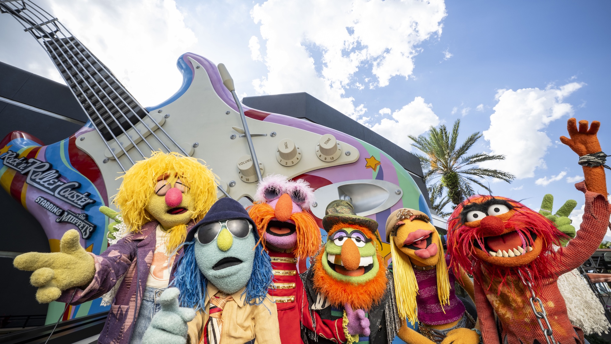The Muppets Electric Mayhem standing in front of the Rock ' N' Roller Coaster guitar outside the ride at Walt Disney World