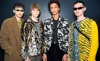 Four Male models pose for a picture with a dark backdrop