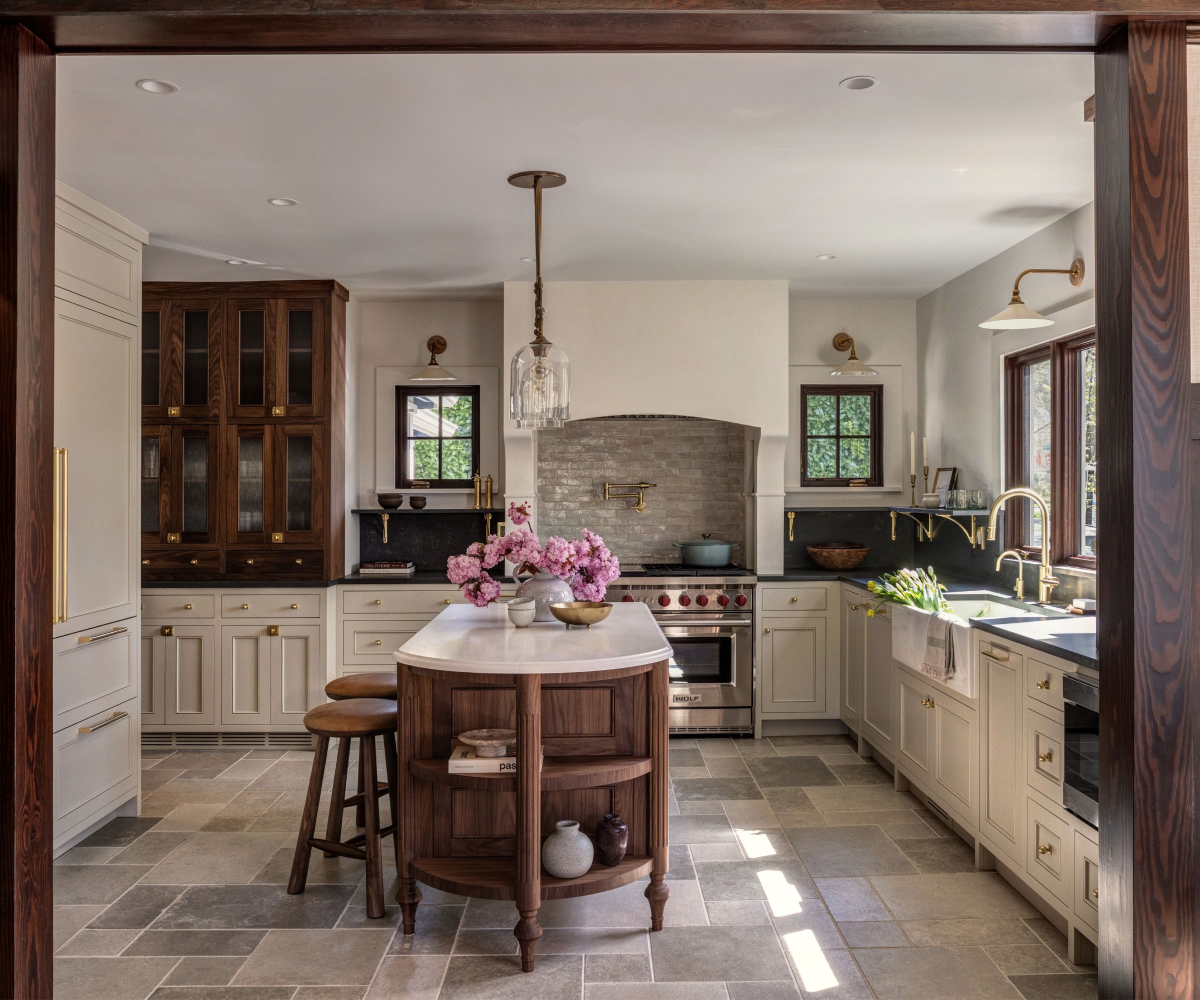 An arts and crafts kitchen with wood and white cabinets and a wooden, curved freestanding island