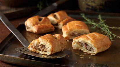 Christmas snack of gourmet sausage rolls and thyme leaves - stock photo