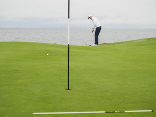 Ben Emerson demonstrating the alignment stick putting drill using three alignment sticks as gates and barriers