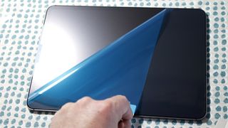 An iPad tablet with a PaperTouch Pro screen protector half-way applied