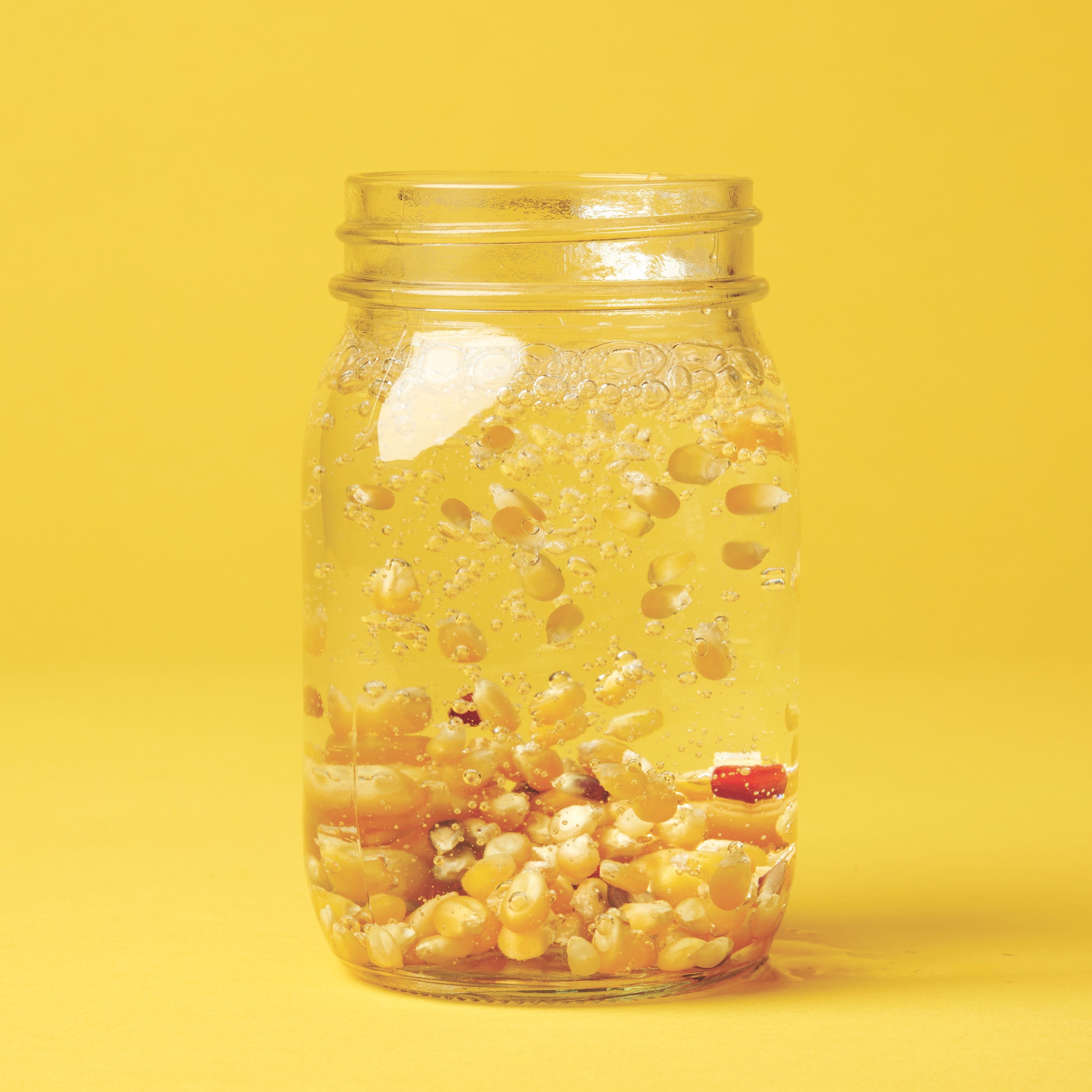 Dancing popcorn in a jar on a yellow background