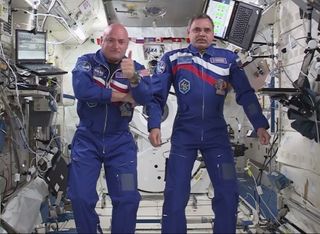 NASA astronaut Scott Kelly (left) gives a thumb's up sign while floating next to fellow one-year crewmate Mikhail Kornienko of Russia on the International Space Station after a video chat with NASA chief Charles Bolden and others on March 30, 2015. The sp