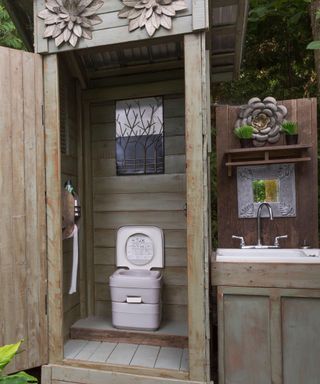 outdoor toilet in wooden cabin with sink
