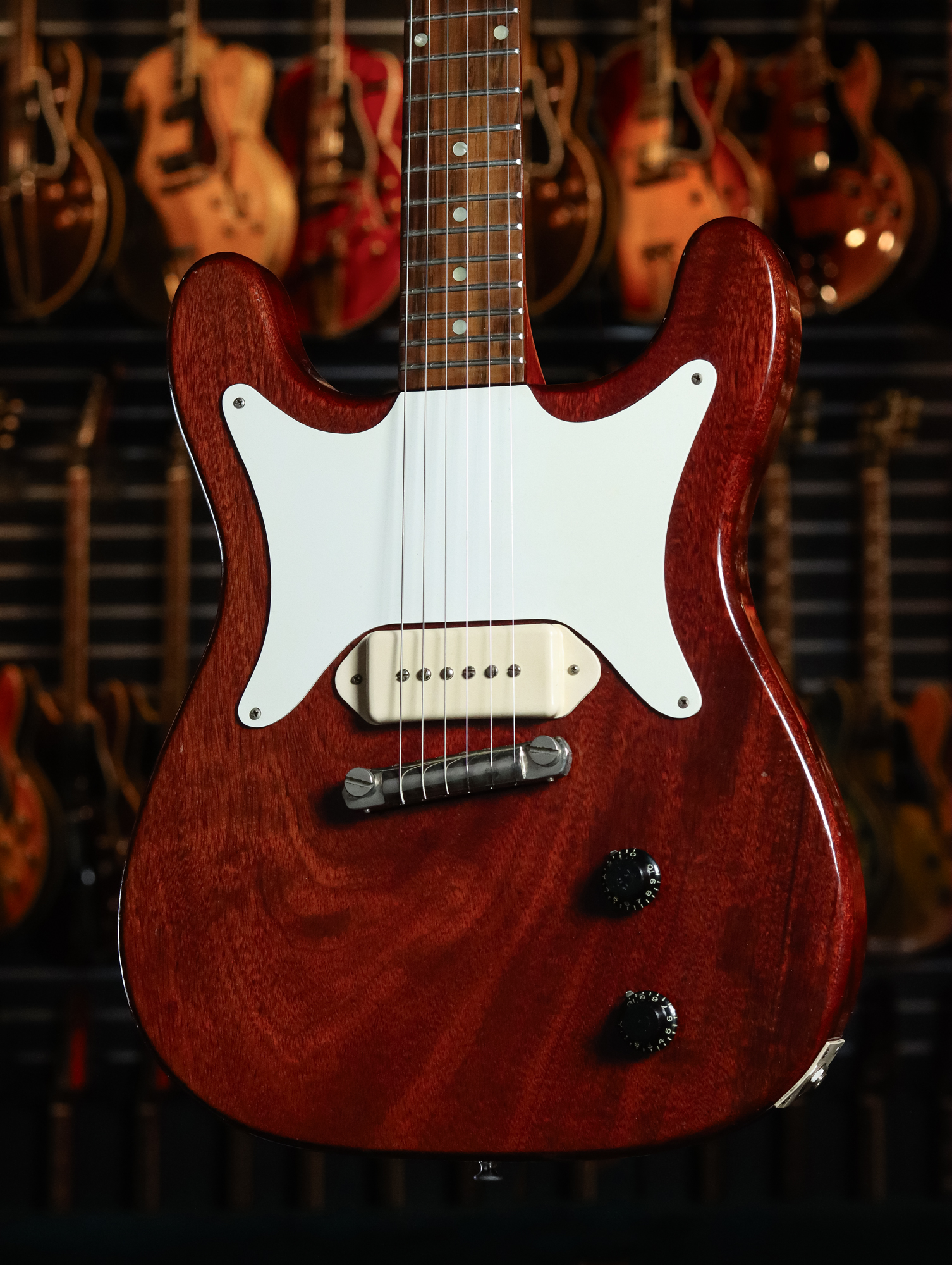 A full-length shot of a 1960 Epiphone Coronet in cherry red.