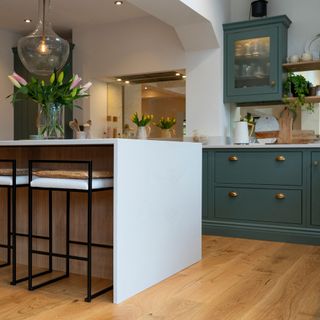 green kitchen with brass cup handles and white kitchen island