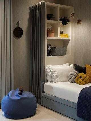 gray and blue boy bedroom scheme with tall storage behind bed, wall lights, textured wallpaper, blue bean bag