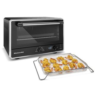A KitchenAid Digital Countertop Oven with Air Fry next to a try of fried prawns on a white background