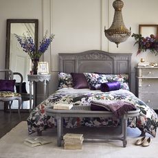 bedroom with white wall and wooden floor and grey bed 