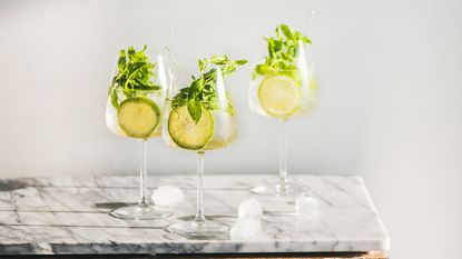 Three glasses of Hugo spritz on a marble style table