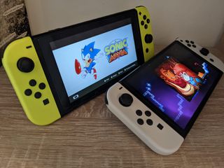 Två stycken Nintendo Switch OLED ligger bredvid varandra och kör spelen Sonic och Celeste.