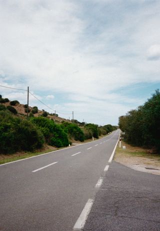 View along an empty road lined with grass verges