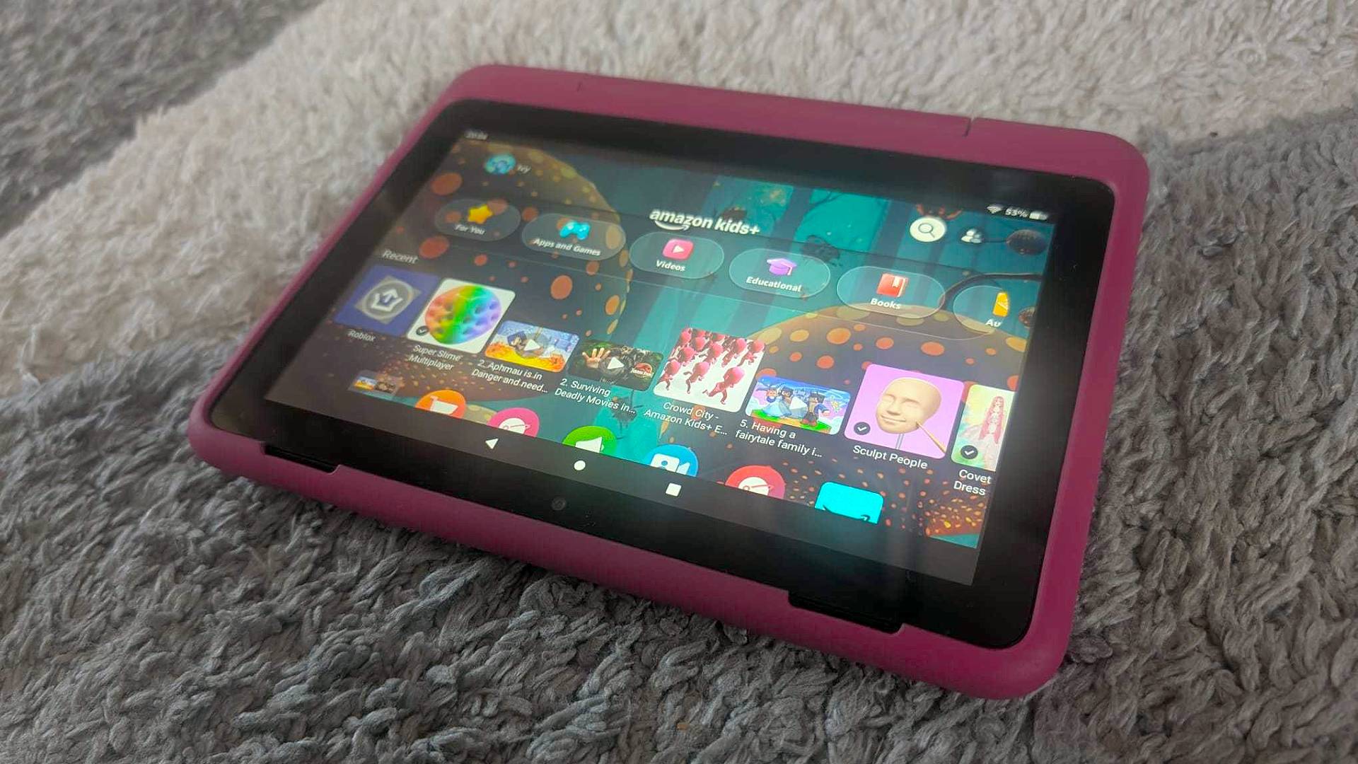 Fire HD 8 Kids Pro tablet on grey carpet with home screen displayed.