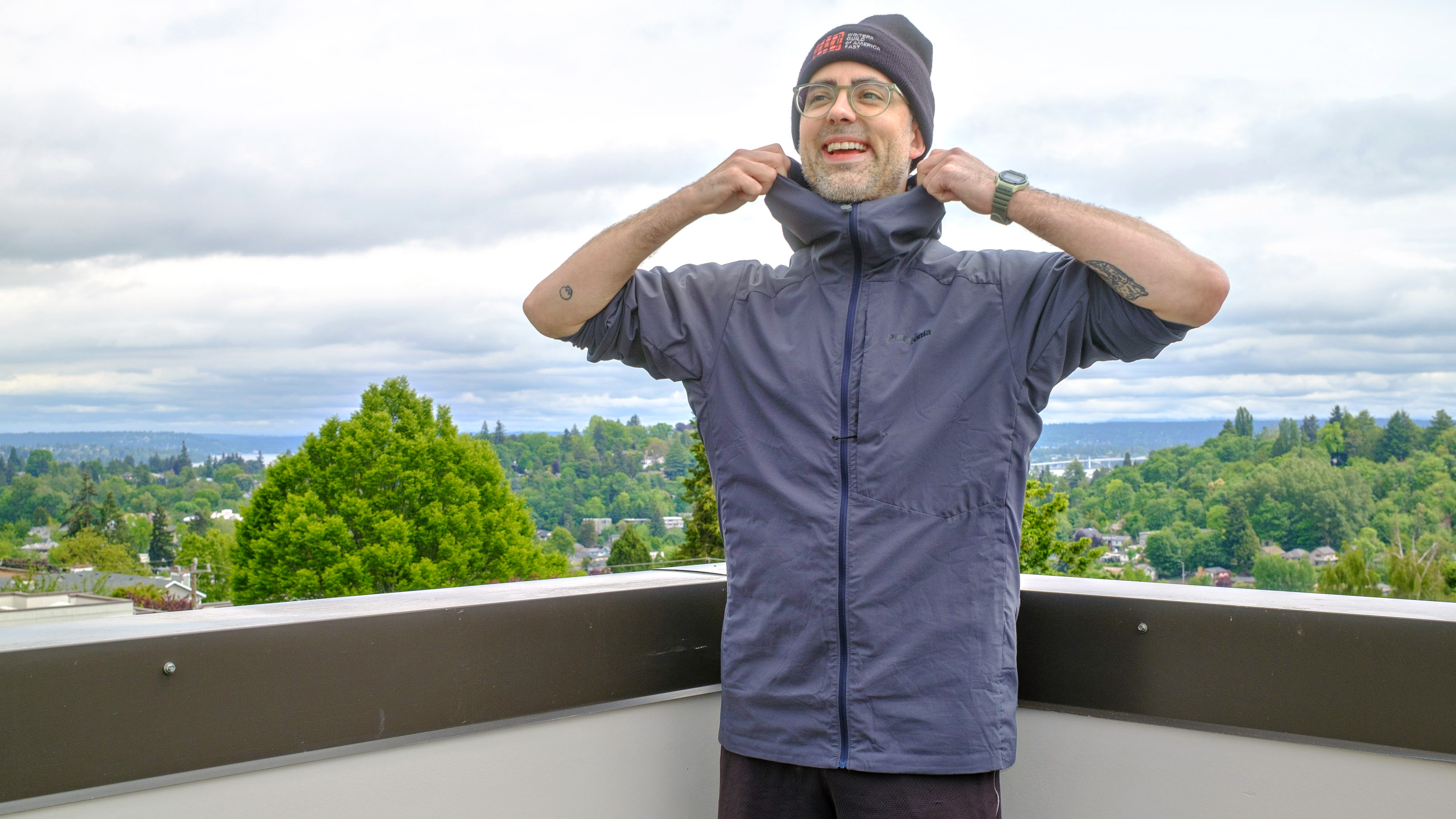 Senior writer Dan Bracaglia wearing the Patagonia Nano-Air Ultralight in grey/blue on the roof of his home in Seattle, Washington with trees and overcast skies in the distance