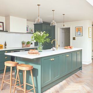 open plan kitchen with wooden flooring and white walls seperated with a green island