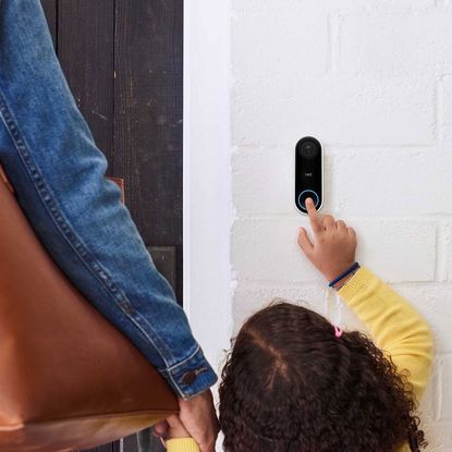 Little boy holding parent's hand and ringing a Google Nest doorbell