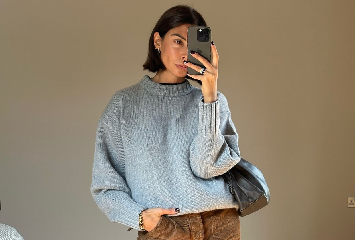 Woman wearing a gray sweater holding up a phone