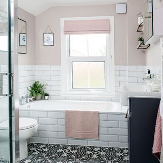 Bathroom with white tiles and pink wall and black and white patterned floor tiles
