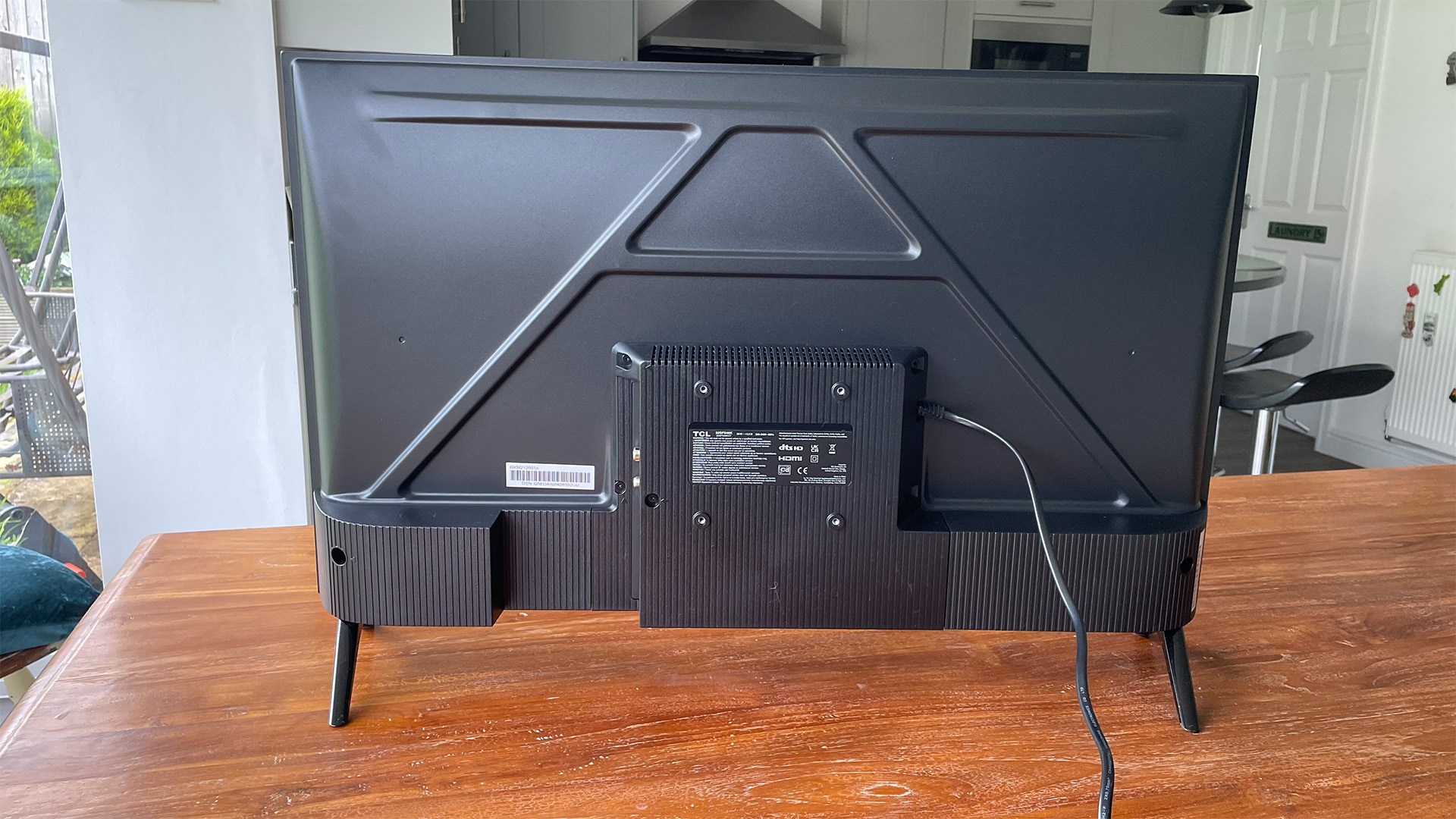 TCL 32SF540K 32英寸电视，图片来自木制桌子上的电视机后部