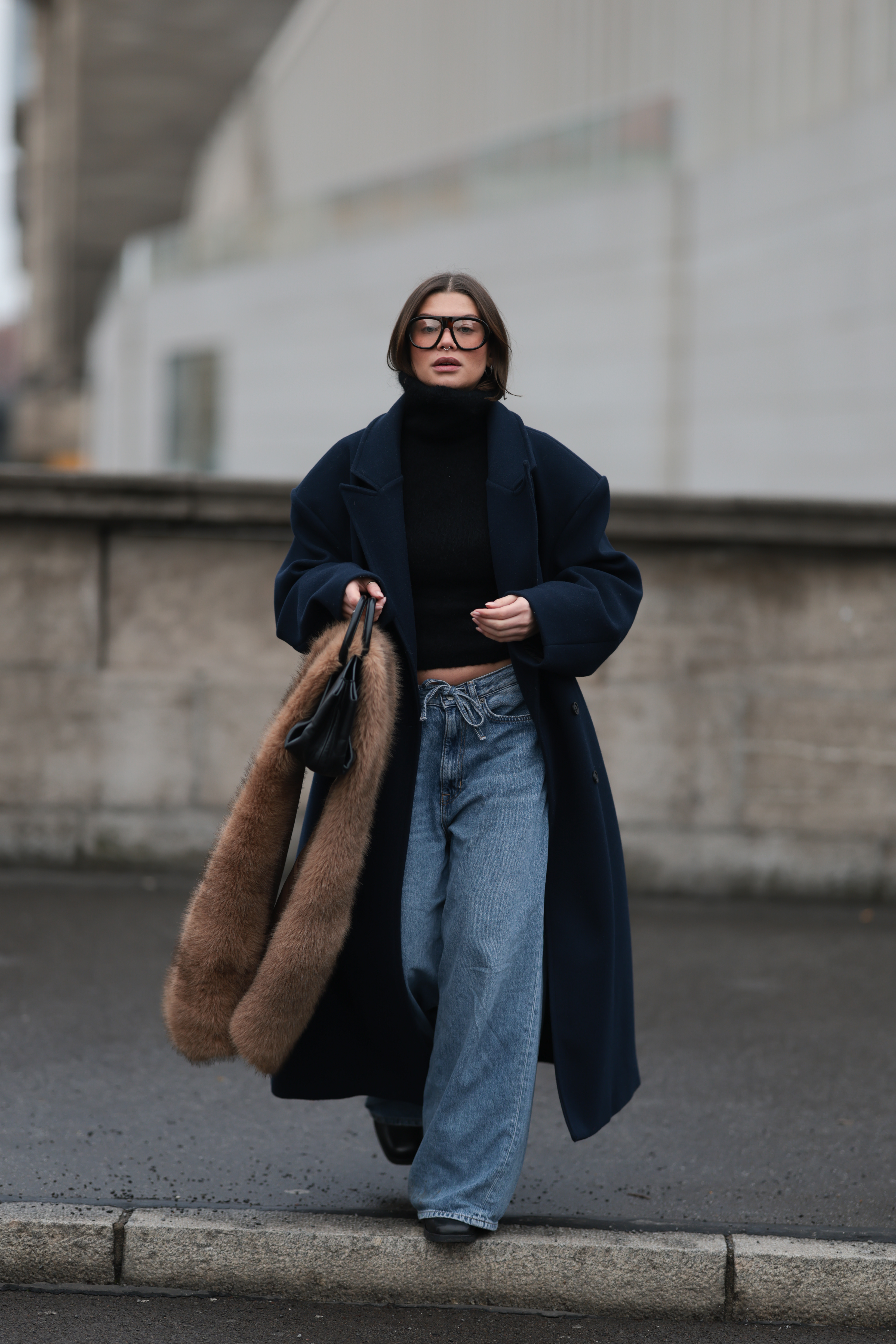 Sophia Geiss is seen wearing the best draw strng jeans. She wears a long, navy blue overcoat, a black &amp;amp; other stories turtleneck sweater, and light blue, wide-leg jeans. The jeans have a drawstring waist. She also wears large, clear-framed Prada glasses. She is carrying a black COS handbag, and draped over the bag is a brown faux fur Mango scarf. She is wearing black &amp;amp; other stories shoes This image was taken on December 10, 2025 in Berlin. It is a Getty image.