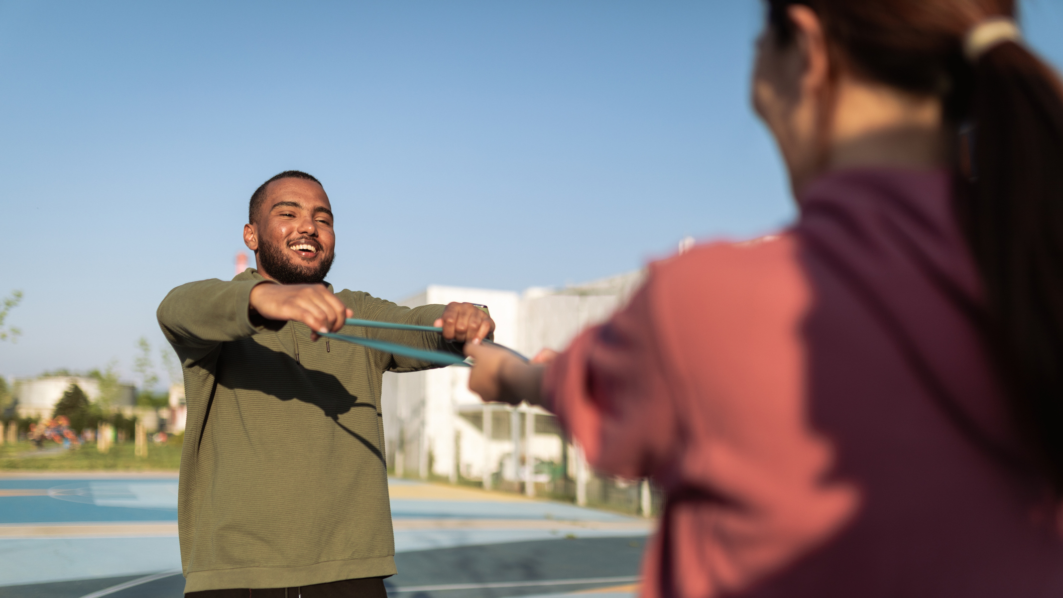 Man and woman exercising outside with the same resistance band