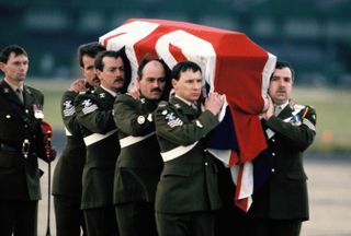 The draped coffin of Major Hugh Lindsay, carried by soldiers, returns in England with Prince Charles, Princess Diana and Sarah Ferguson, Duchess of York at RAF Northolt on March 12, 1988 in London, England