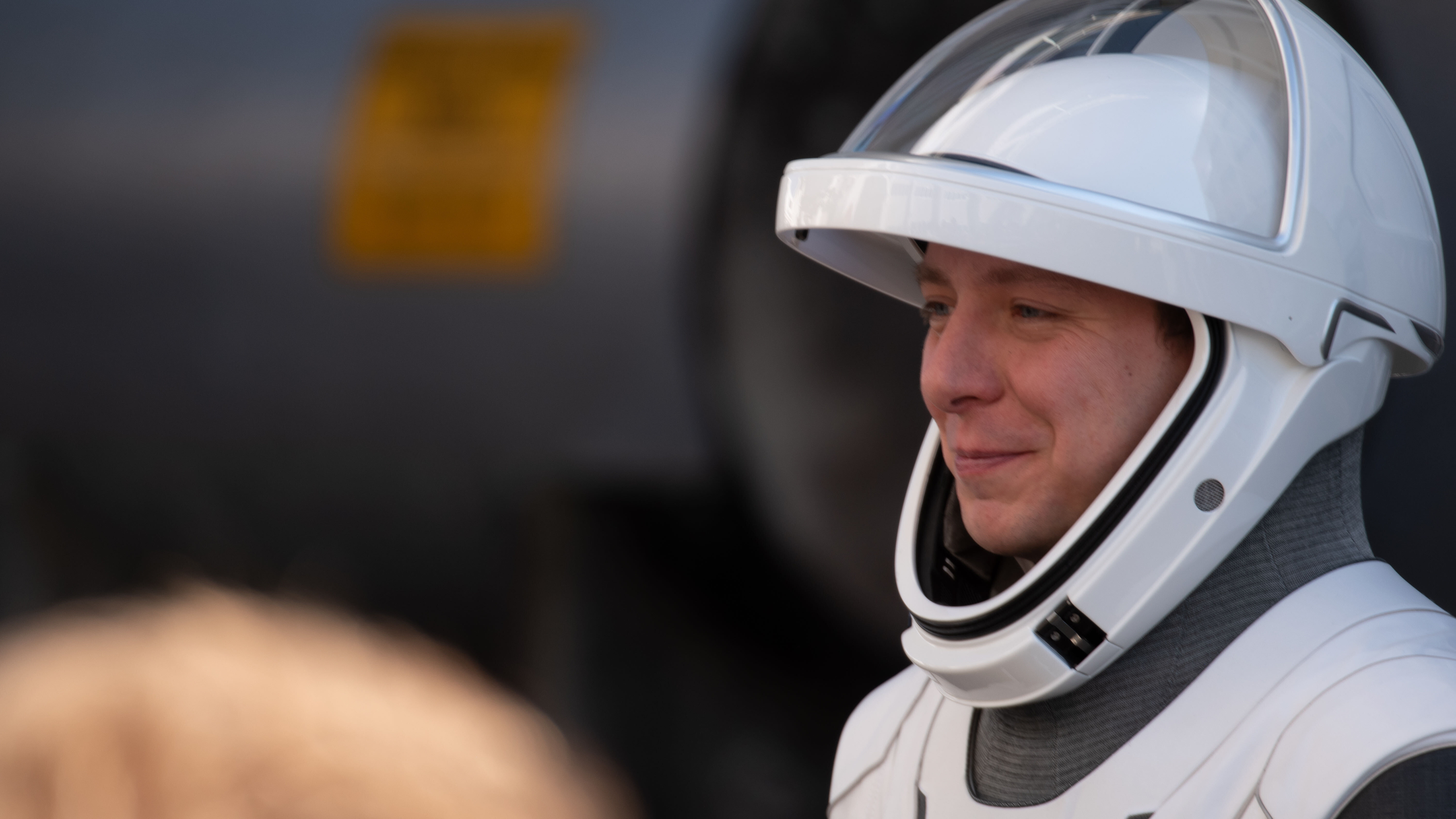 astronauts walk out of a building and board black cars.