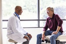 Male doctor talking with senior man in exam room