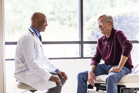 Male doctor talking with senior man in exam room