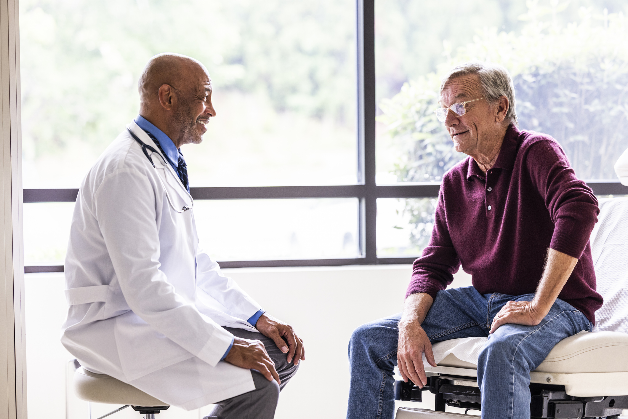 Male doctor talking with senior man in exam room