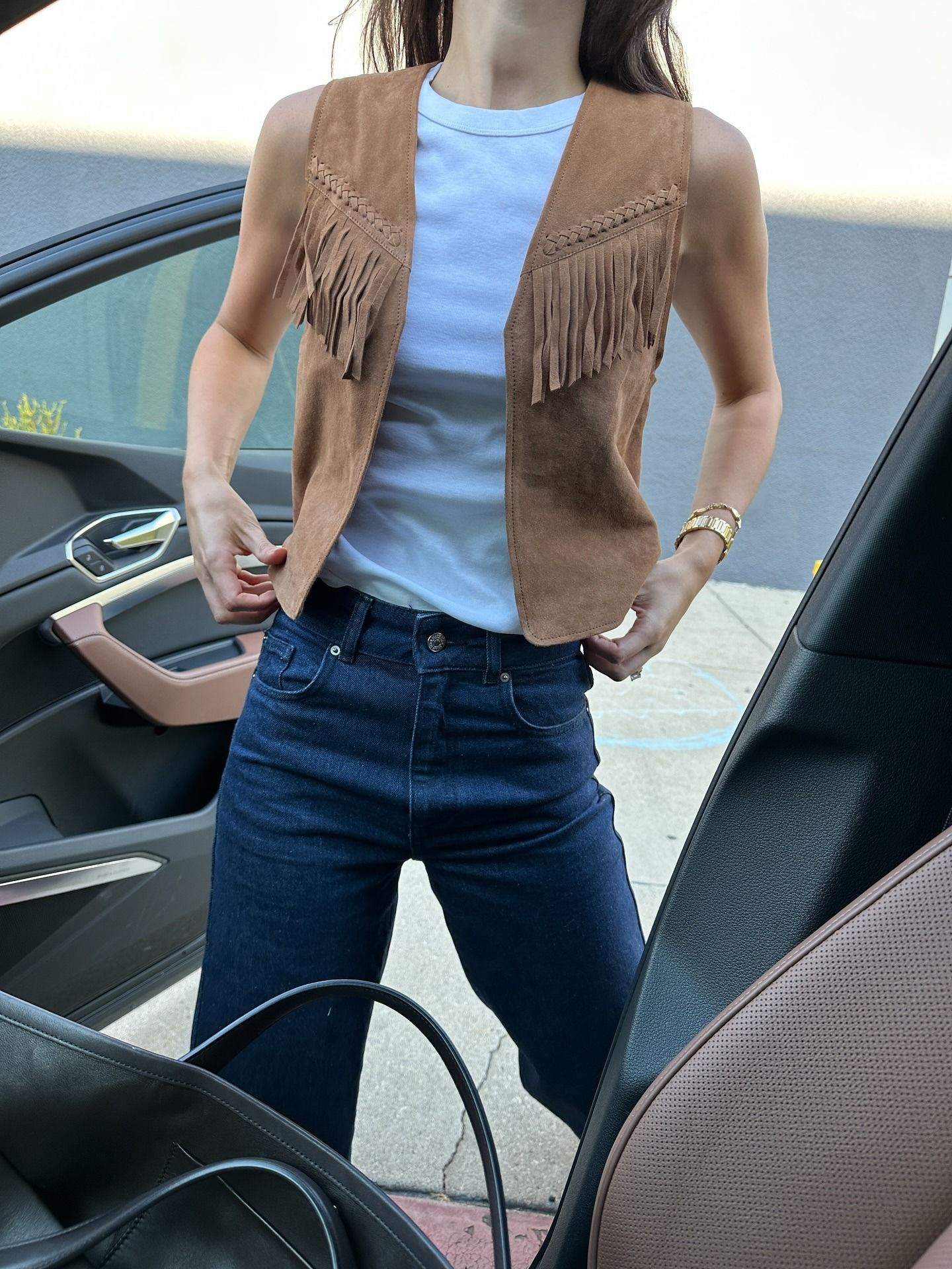 @ilanatorbiner wearing a white tee, fringe vest, and jeans.