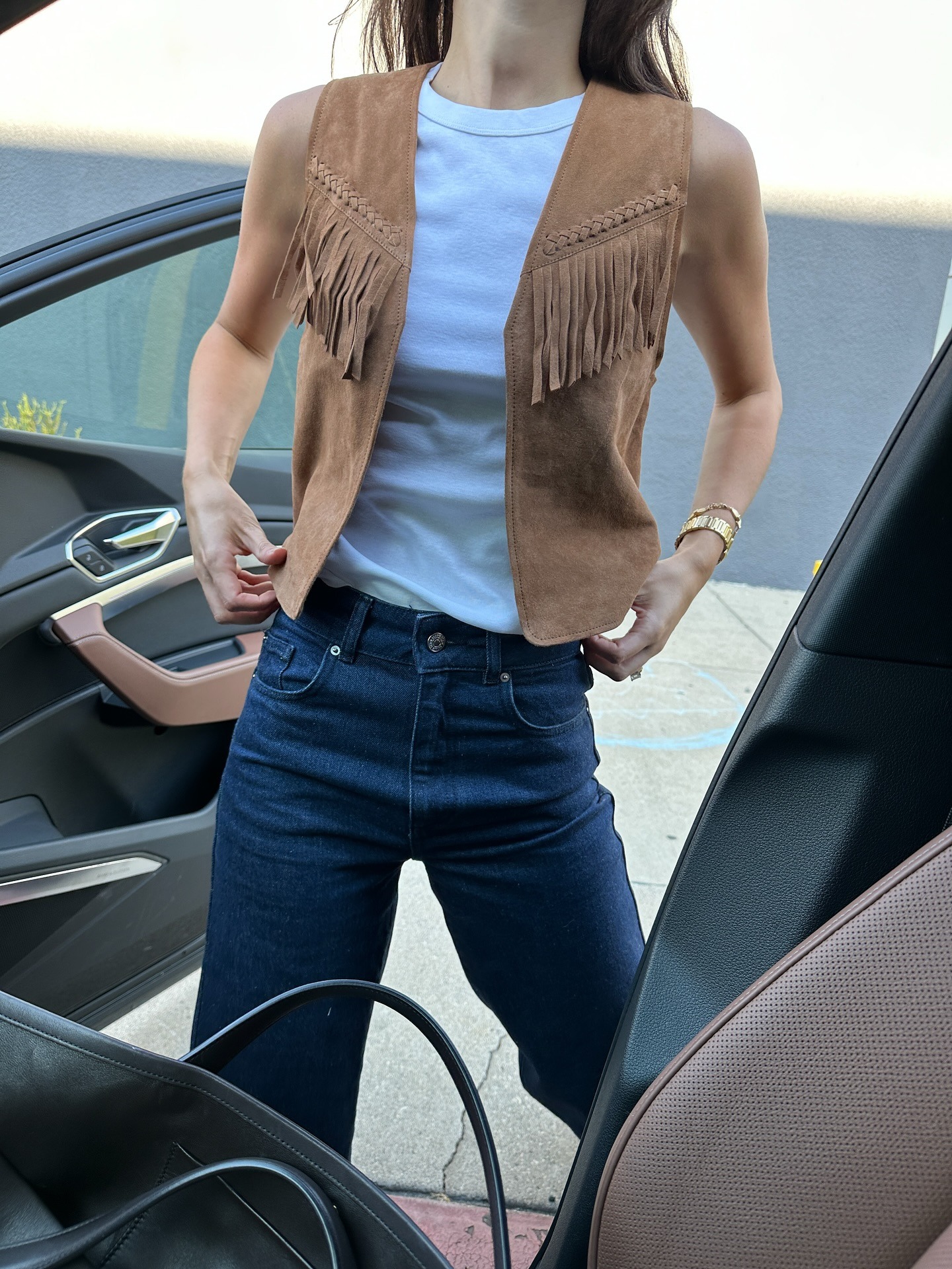 @ilanatorbiner wearing a white tee, fringe vest, and jeans.