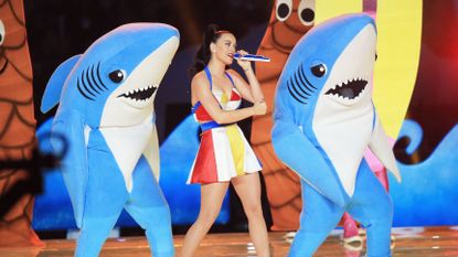 Katy Perry performing with two people in shark costumes.