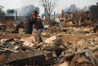 Taken on January 9, 2025, two people embrace while inspecting a property destroyed by the Eaton Fire