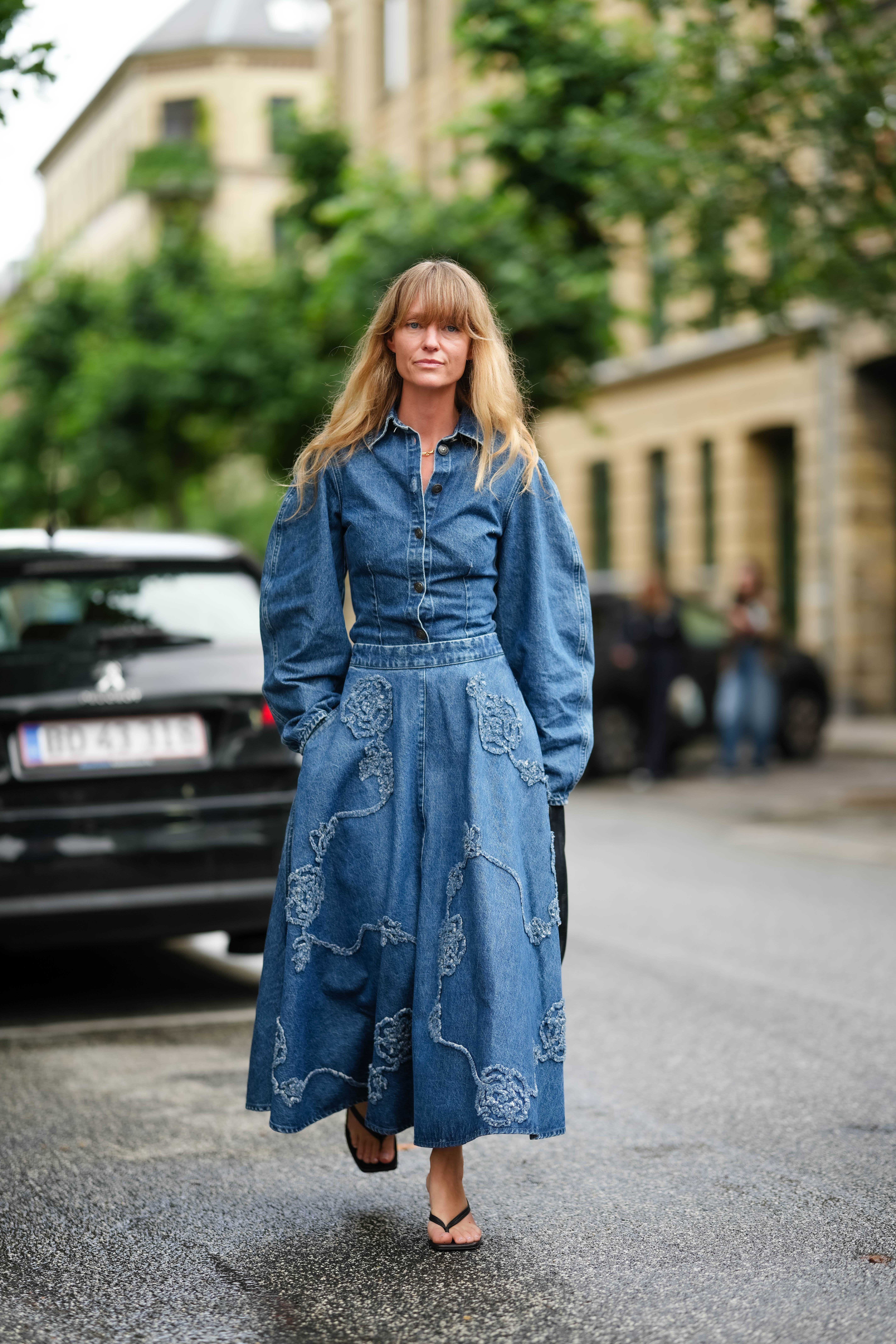 a woman at fashion week wearing a denim shirt and skirt