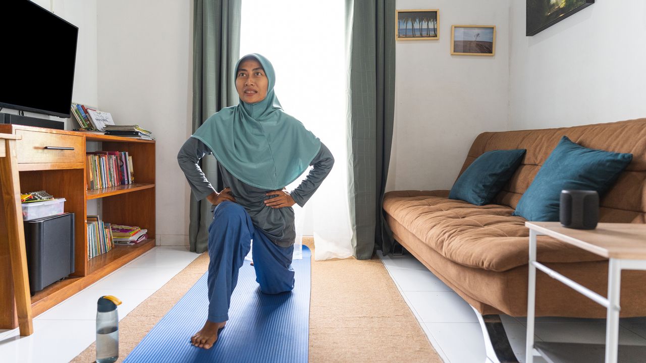 Woman working out at home in living room on a yoga mat