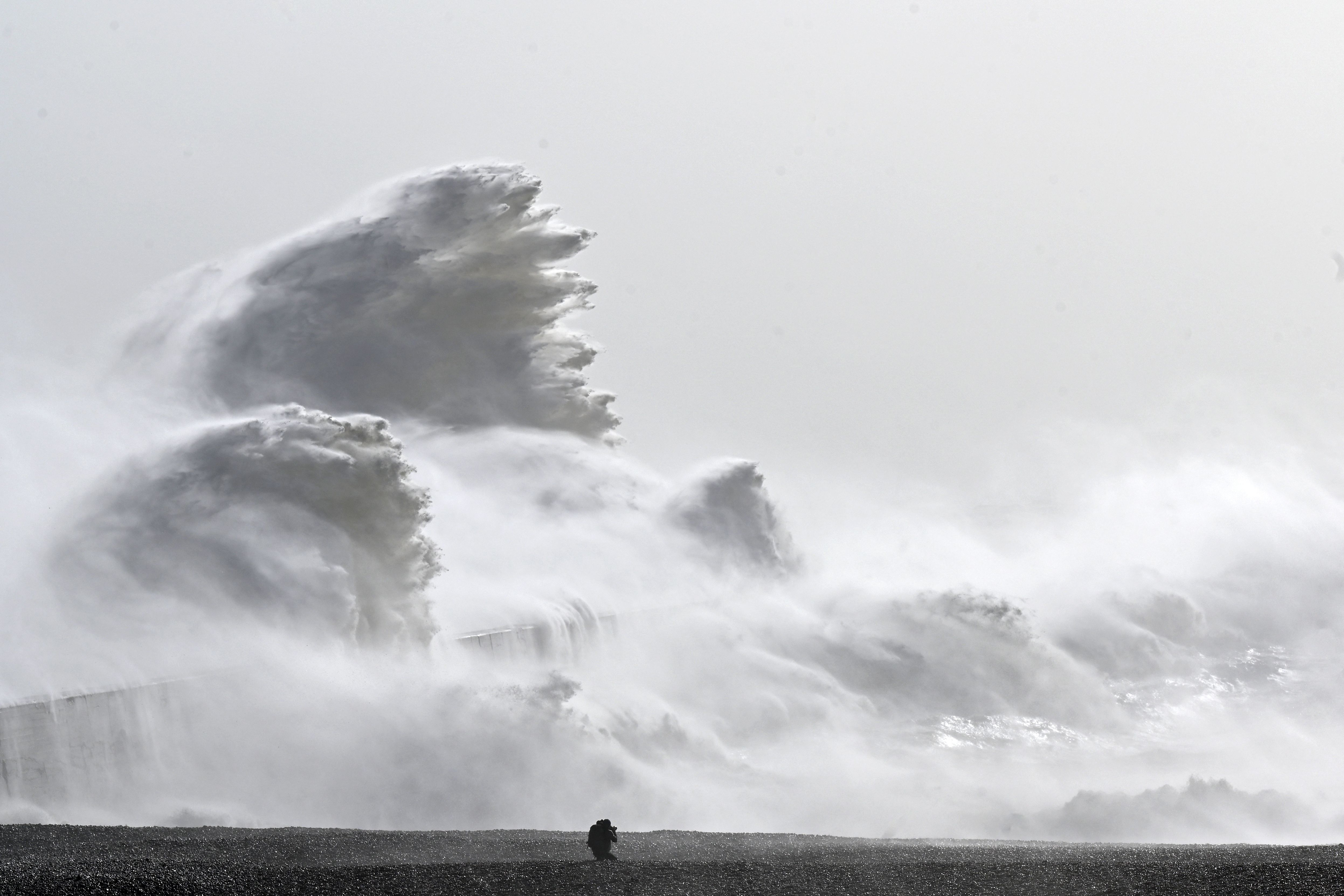 a monotone image showing huge waves crashing down over a wall.