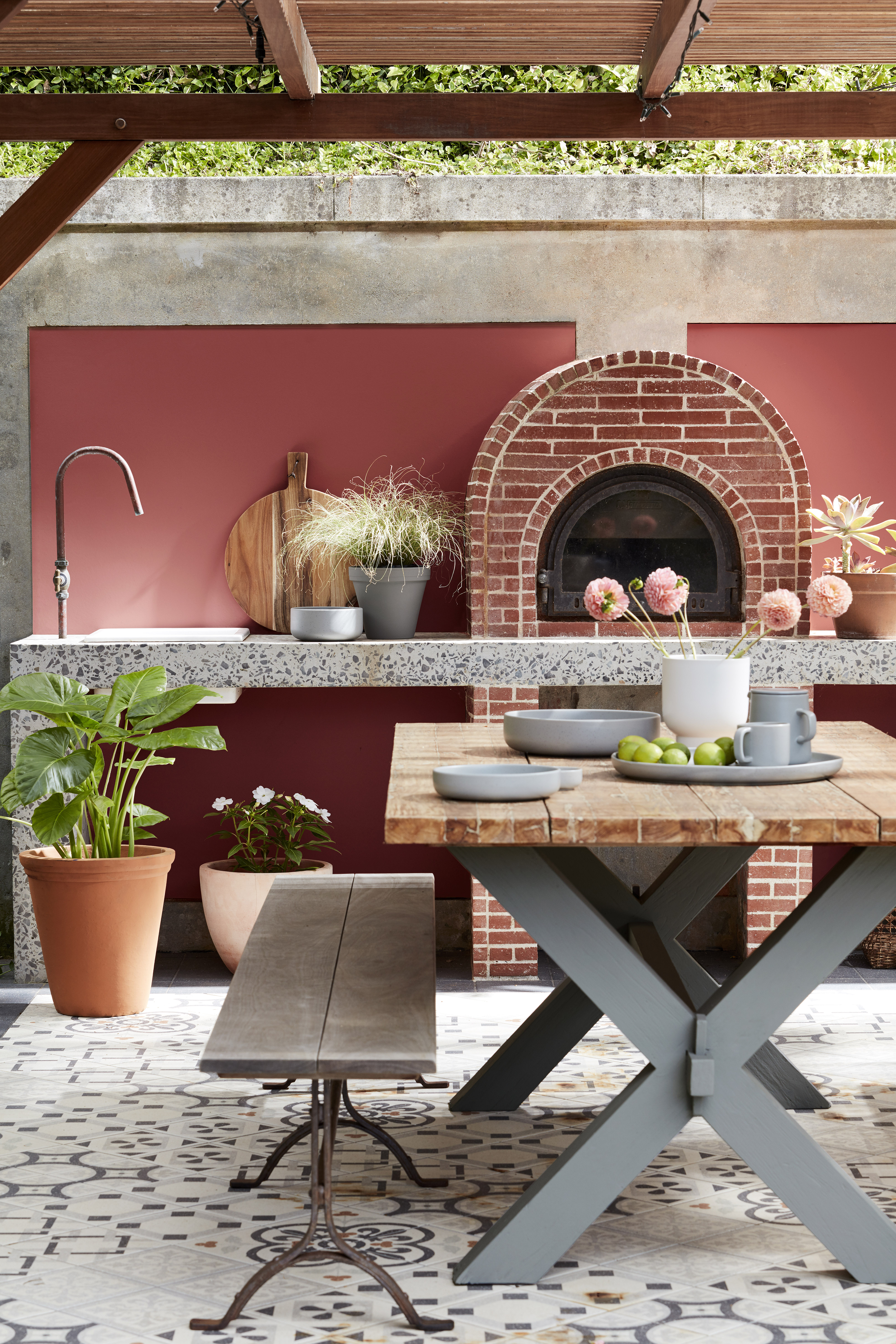 An outdoor section with a red painted wall, and a built in grill within a stone wall