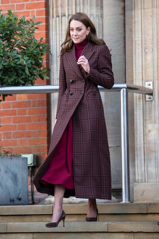 Kate Middleton wearing a brown plaid coat and burgundy turtleneck