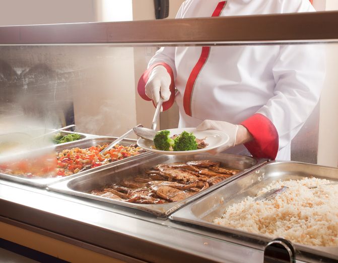 A cafeteria worker makes up a plate of food.