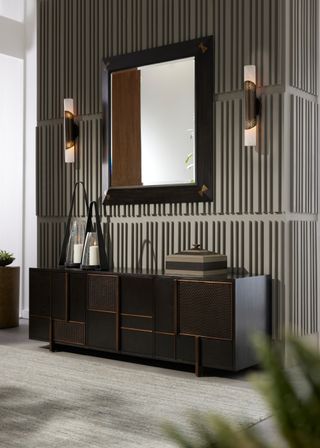 A console table with metal accents and brass sconces on the walls above