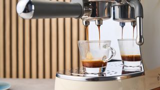 a double shot of espresso being poured by a cream-colored retro espresso machine by italian brand smeg