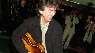 George Harrison plays a guitar at the preview part for Eric Clapton's Christie's guitar auction to raise funds for his Crossroads Centre, 1999