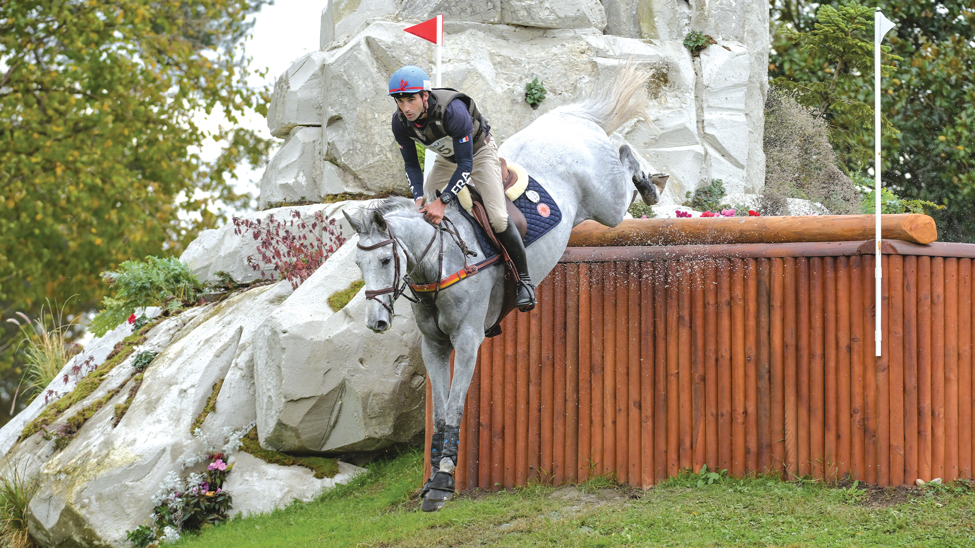 Astier Nicolas jumping down a large cross-country step on grey horse at Pau Horse Trials 