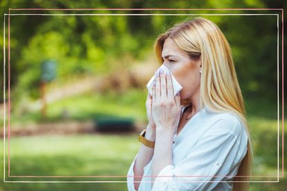 A woman stood in a field holding a tissue to her nose