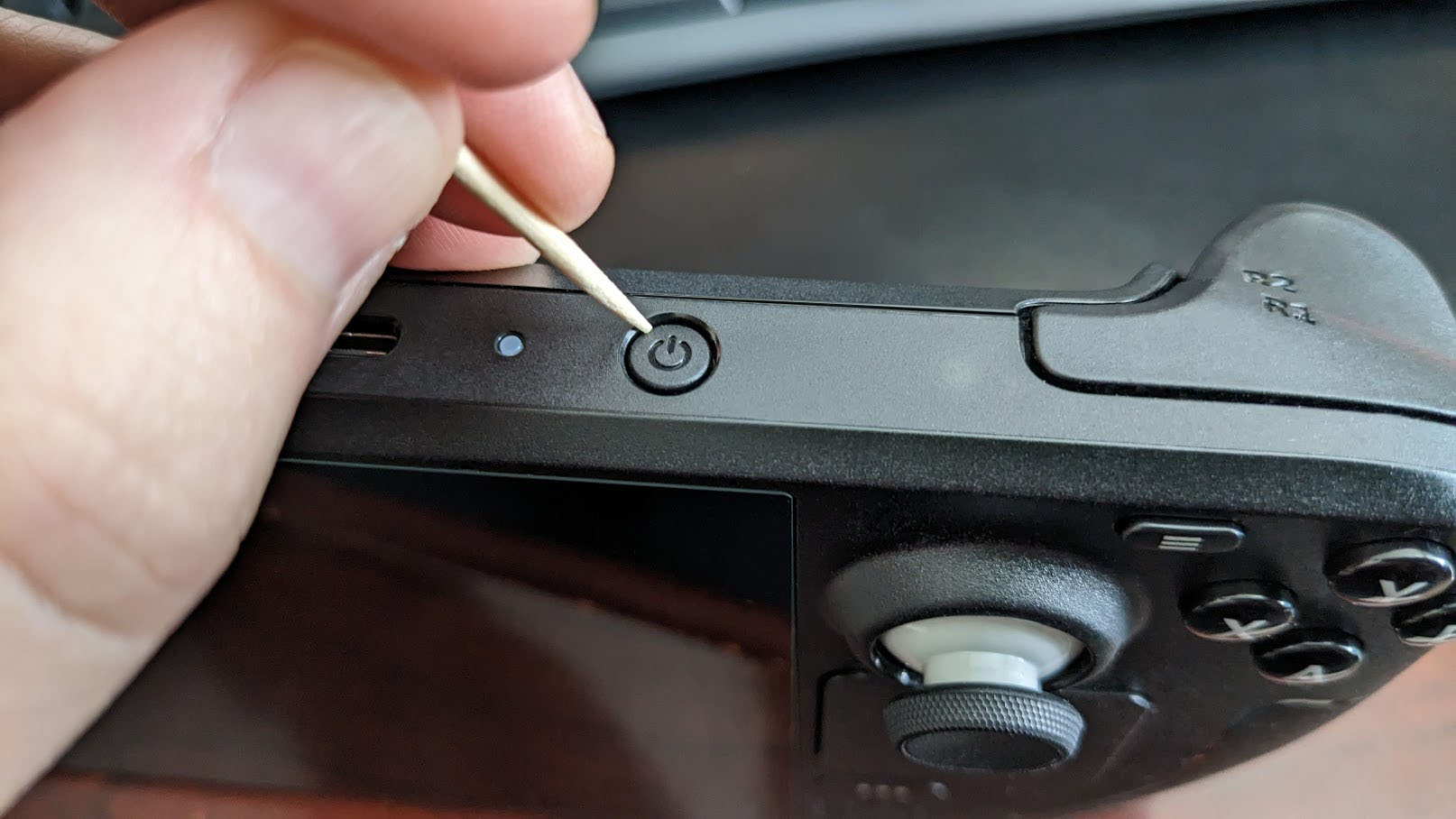 Using a toothpick on the Steam Deck power button.