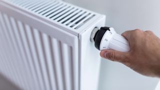 Person turning a dial on a radiator thermostat